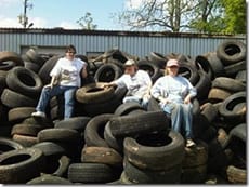 Volunteers Karen Hennessey Grimm, Nancy Hennessey, and Michelle Rice rest on a pile of tires after a successful Roundup. Photo by Nancy Hennessey.