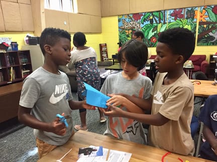 Boys discuss the design for their custom paper airplane in this high flying lesson on aerodynamics. Photo by Jason Raines of The Flying Classroom.